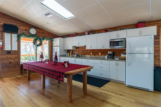 a kitchen with stainless steel appliances granite countertop a refrigerator a sink dishwasher a stove and a dining table with wooden floor