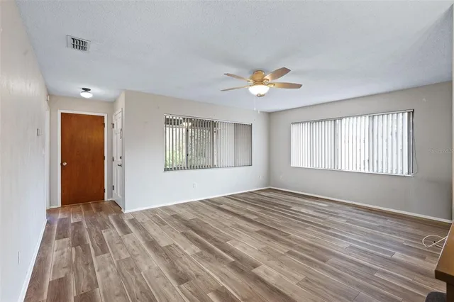 a view of empty room with wooden floor and fan