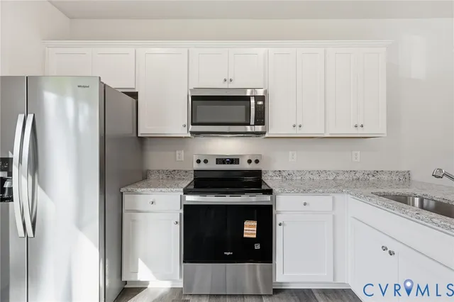a kitchen with granite countertop white cabinets and stainless steel appliances