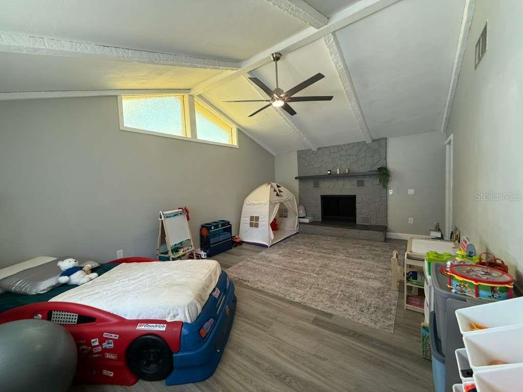 2021 Valley Drive Dunedin, FL 34698 - Photo 23 of 79 a spacious bedroom with a bed next to a window and a chandelier