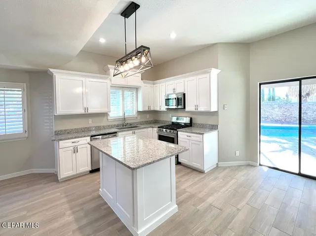a kitchen with a center island wooden floor stainless steel appliances and window