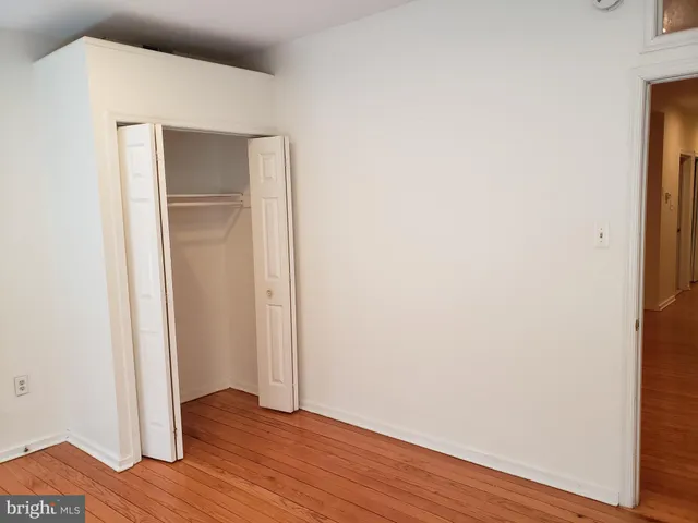 a view of an empty room with wooden floor and closet