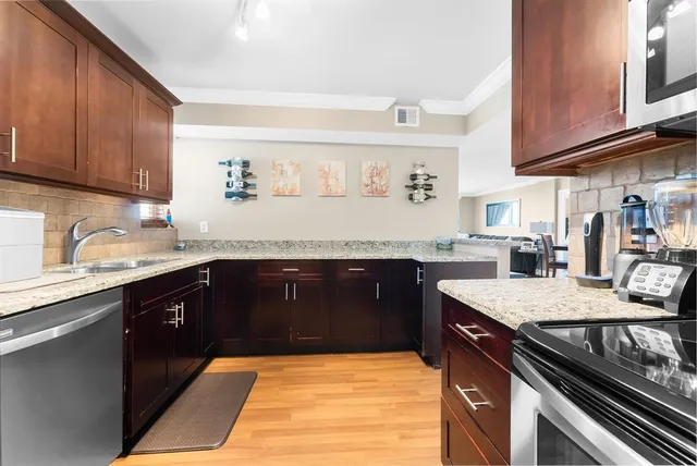 a kitchen with granite countertop a sink cabinets and stainless steel appliances