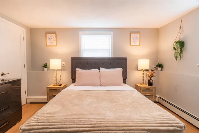 a large bed sitting in a bedroom next to a window with potted plant
