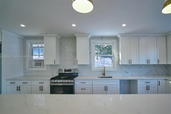 a kitchen with kitchen island granite countertop a stove sink and cabinets