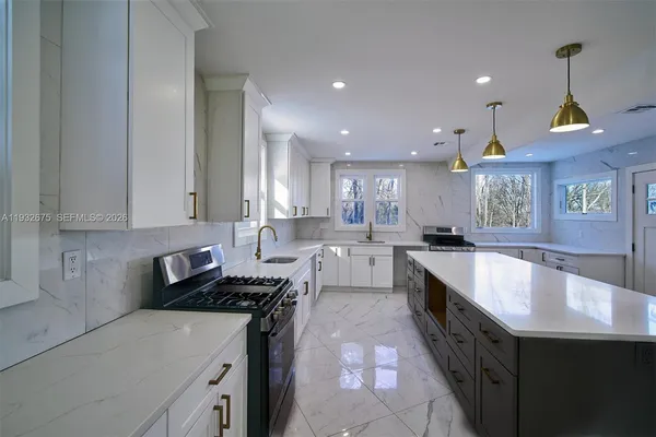a large kitchen with stainless steel appliances granite countertop a sink a stove and a wooden cabinets