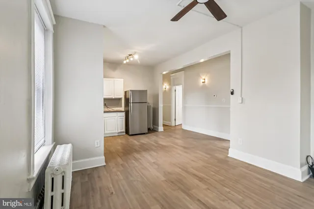 a view of kitchen and empty room with wooden floor