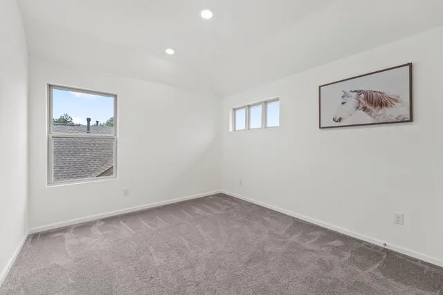 an empty room with a painting and a window