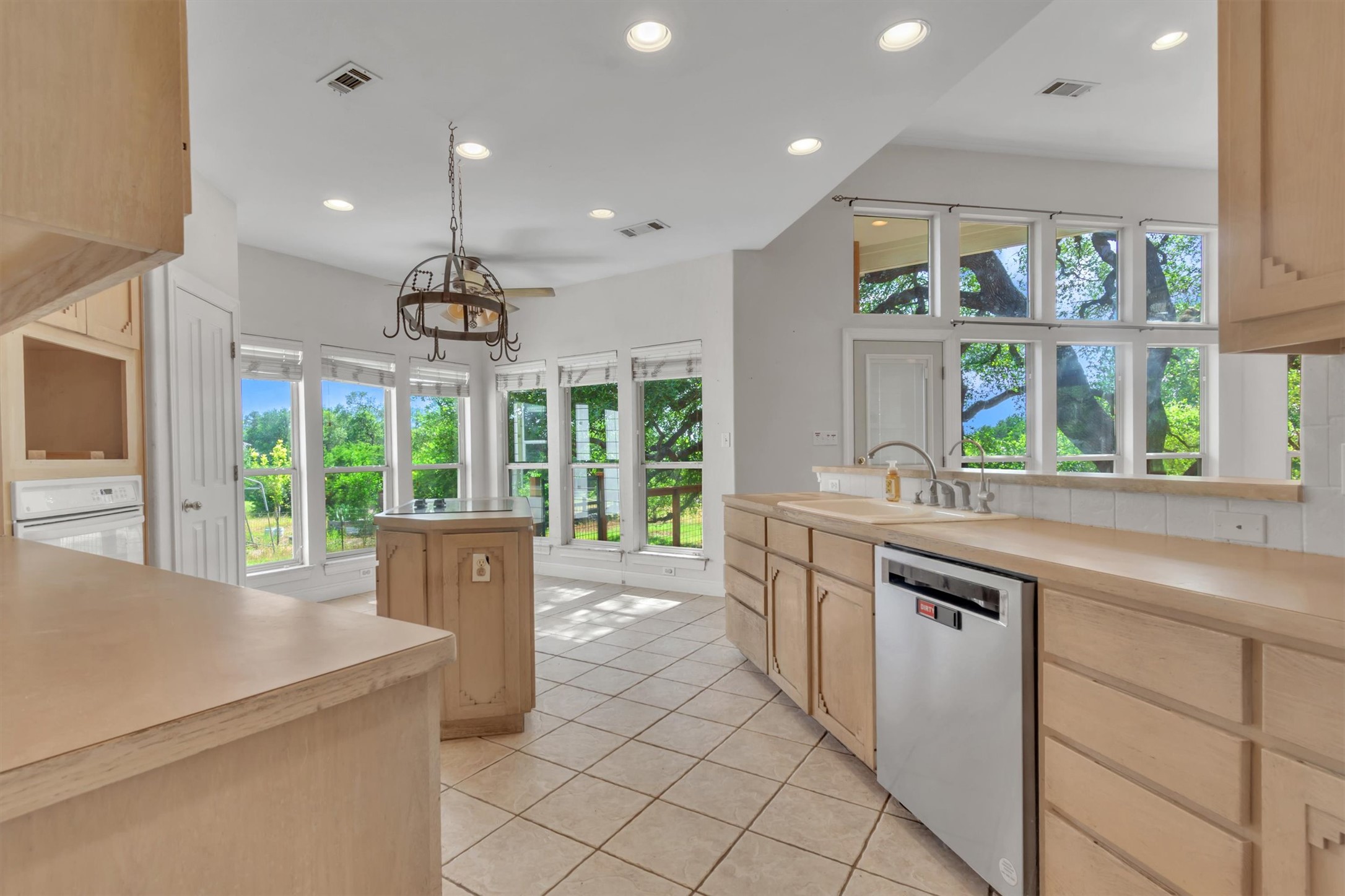 1120 Meadow Ridge Drive Austin, TX 78737 - Photo 15 of 40 A naturally illuminated kitchen with ample counter space and a central island overlooking abundant exterior greenery.