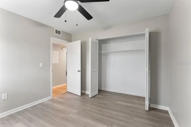 an empty room with wooden floor and ceiling fan