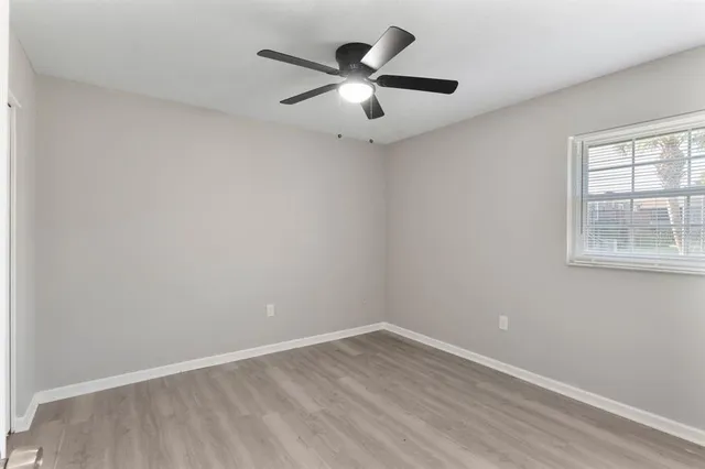 an empty room with wooden floor and ceiling fan