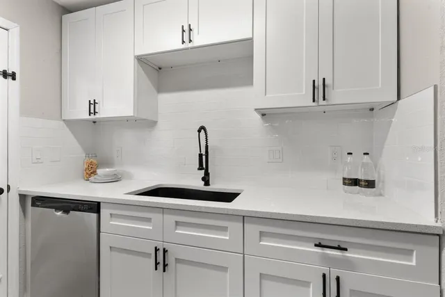 a kitchen with white cabinets and sink