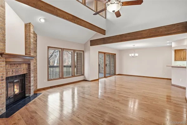 a view of an empty room with window and wooden floor