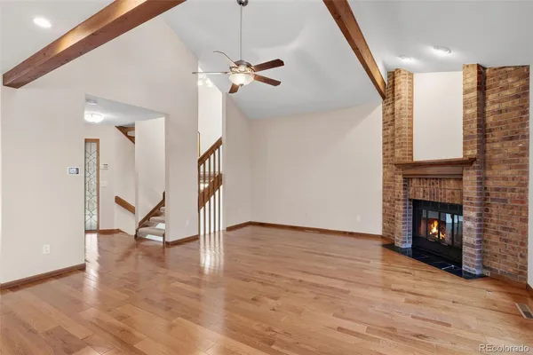 a view of an empty room with wooden floor a fireplace