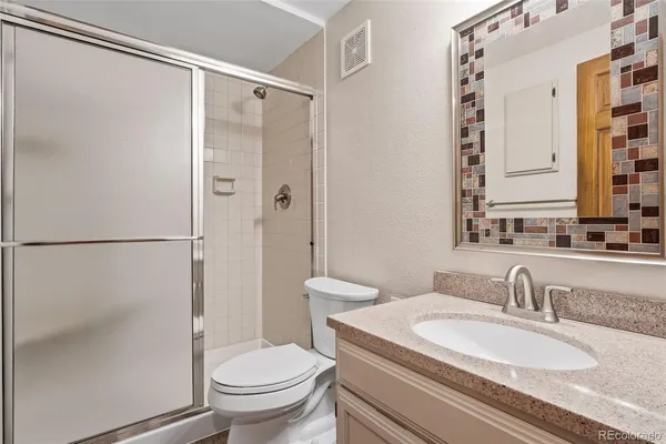 a bathroom with a granite countertop sink toilet and shower