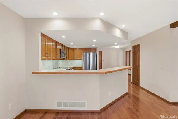 a view of a kitchen with stainless steel appliances wooden floor and large window