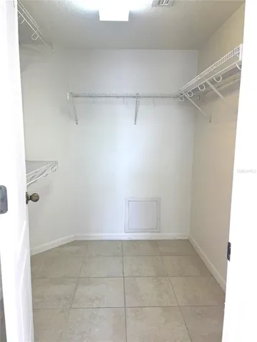 an empty room with a chandelier fan and windows