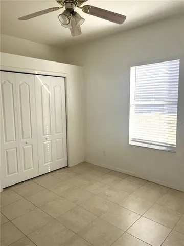 an empty room with a ceiling fan and window