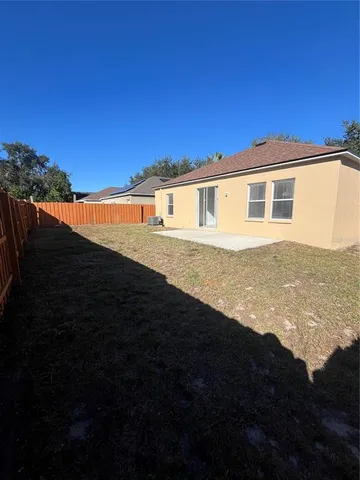 a view of house with backyard and bushes
