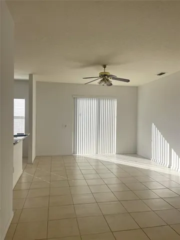 an empty room with a ceiling fan and glass door shower