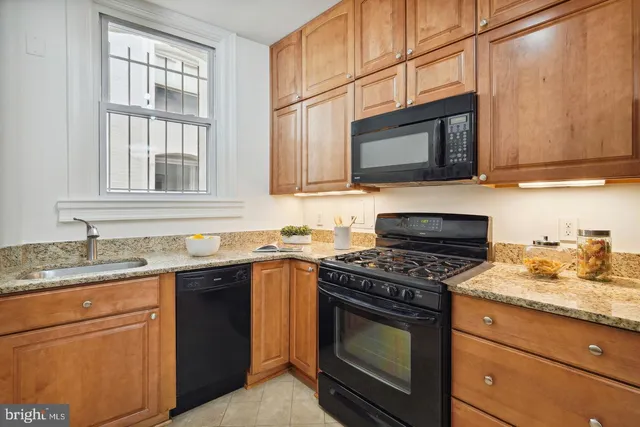 a kitchen with granite countertop a sink stove and microwave