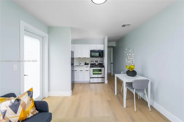 a kitchen with stainless steel appliances wooden floor and a refrigerator
