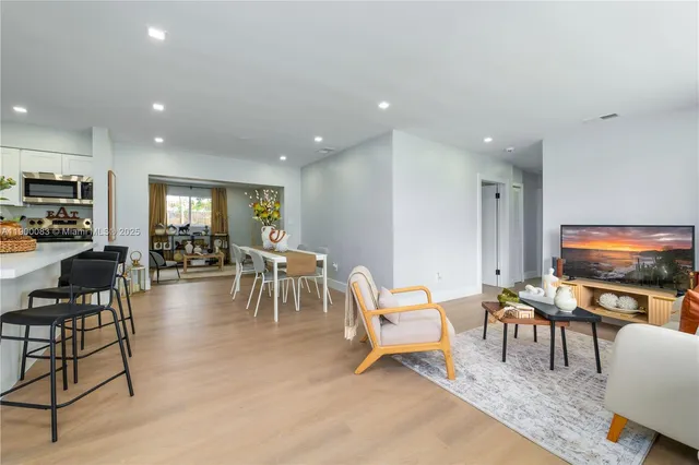 a living room with furniture and a flat screen tv with kitchen view