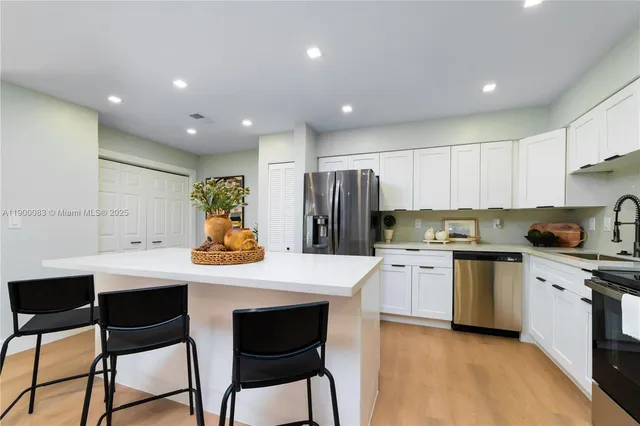 a kitchen with stainless steel appliances granite countertop a table chairs sink refrigerator and cabinets