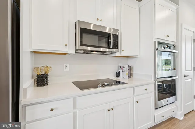 a kitchen with stainless steel appliances granite countertop white cabinets and a stove