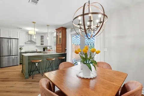 a kitchen with stainless steel appliances granite countertop a dining table chairs and white cabinets