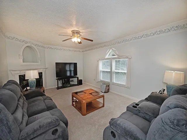 a living room with furniture a flat screen tv and a window