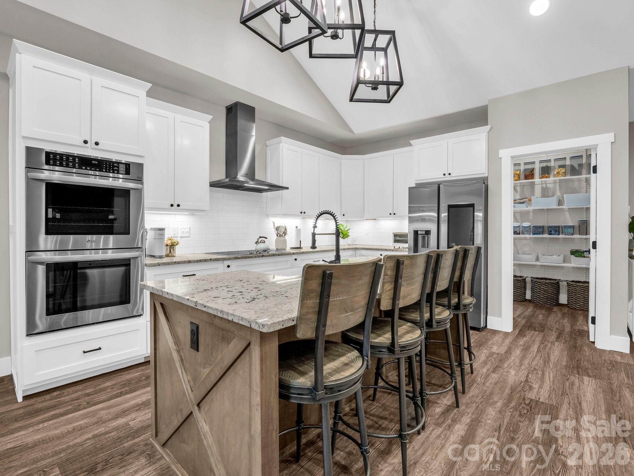 5717 Turnpike Road Horse Shoe, NC 28742 - Photo 25 of 36 a kitchen with stainless steel appliances granite countertop a stove top oven a refrigerator a sink and chairs with wooden floor