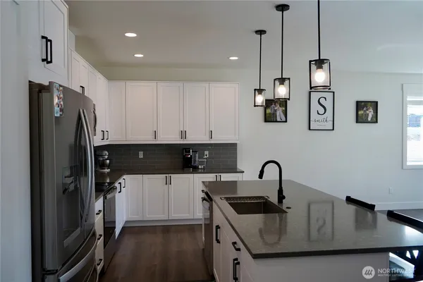 a kitchen with stainless steel appliances kitchen island granite countertop a stove a refrigerator a kitchen island a dining table and chairs with wooden floor