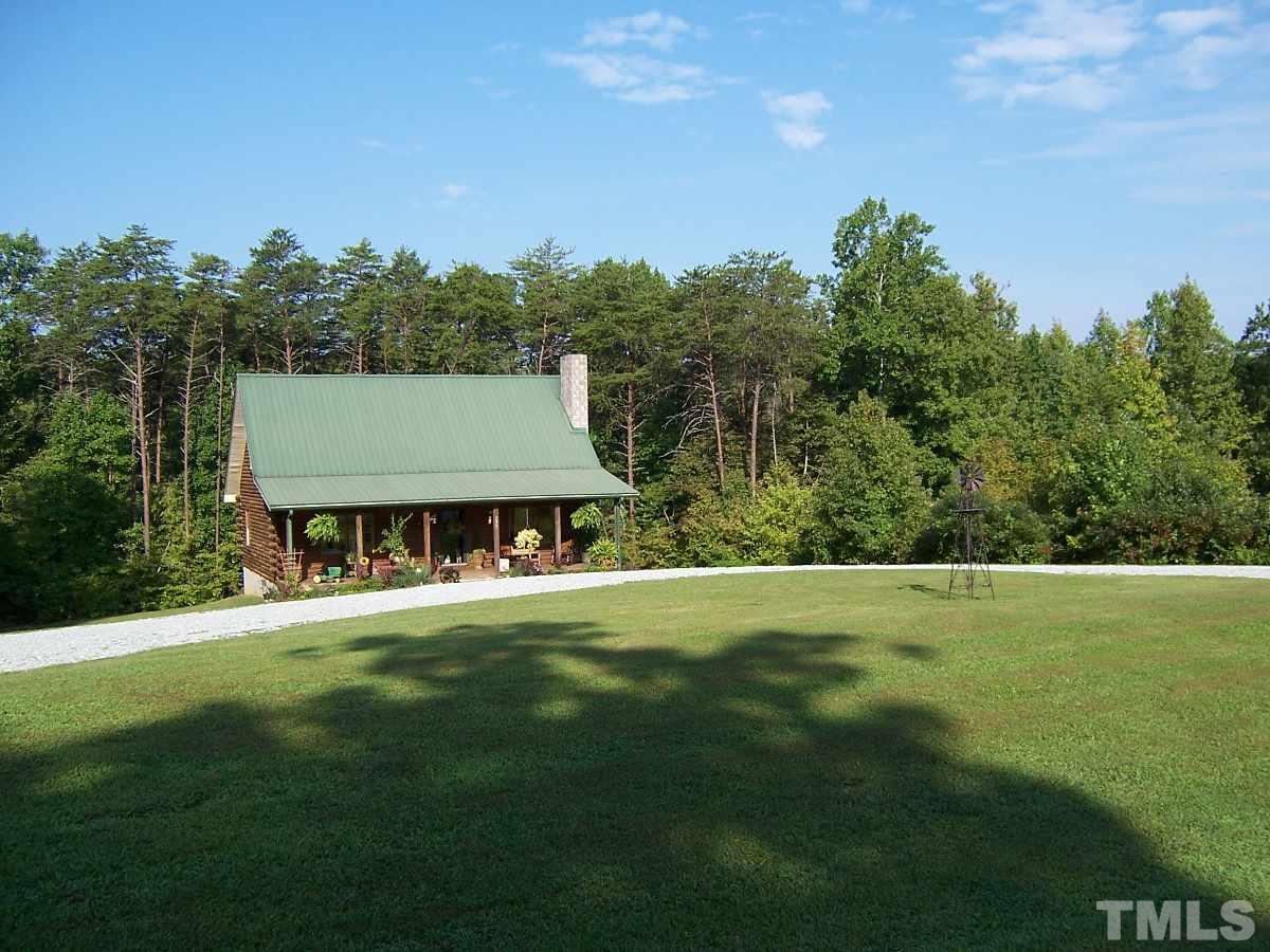 a view of a house with a big yard and large trees
