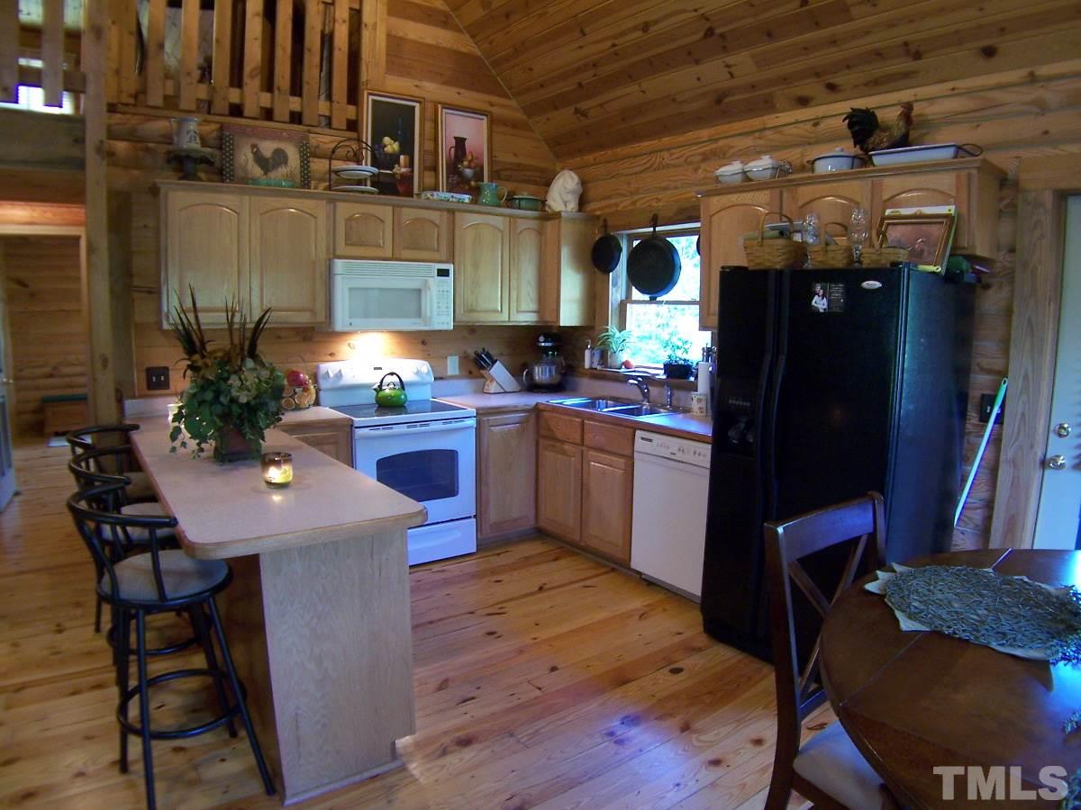 239 Rocky Ridge Road Leasburg, NC 27291 - Photo 5 of 23 a kitchen with stainless steel appliances granite countertop a sink dishwasher a stove a refrigerator a dining table and chairs with wooden floor