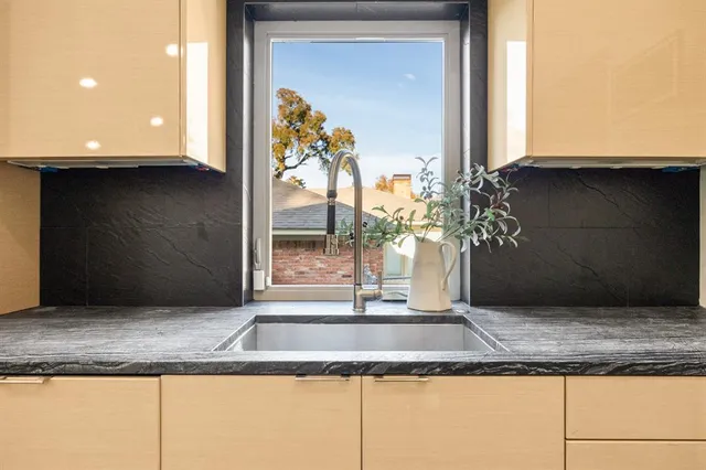 a large kitchen with stainless steel appliances kitchen island granite countertop a large counter top a stove a chimney a sink and a large window