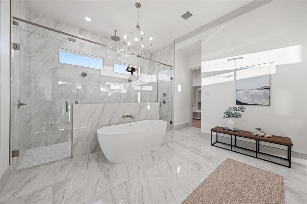 724 Cooper Trail Weatherford, TX 76087 - Photo 25 of 37 Spacious bathroom featuring a freestanding soaking tub, an expansive glass-enclosed shower with multiple showerheads, marble-patterned tile flooring, a coordinating marble-patterned shower surround, and a contemporary chandelier