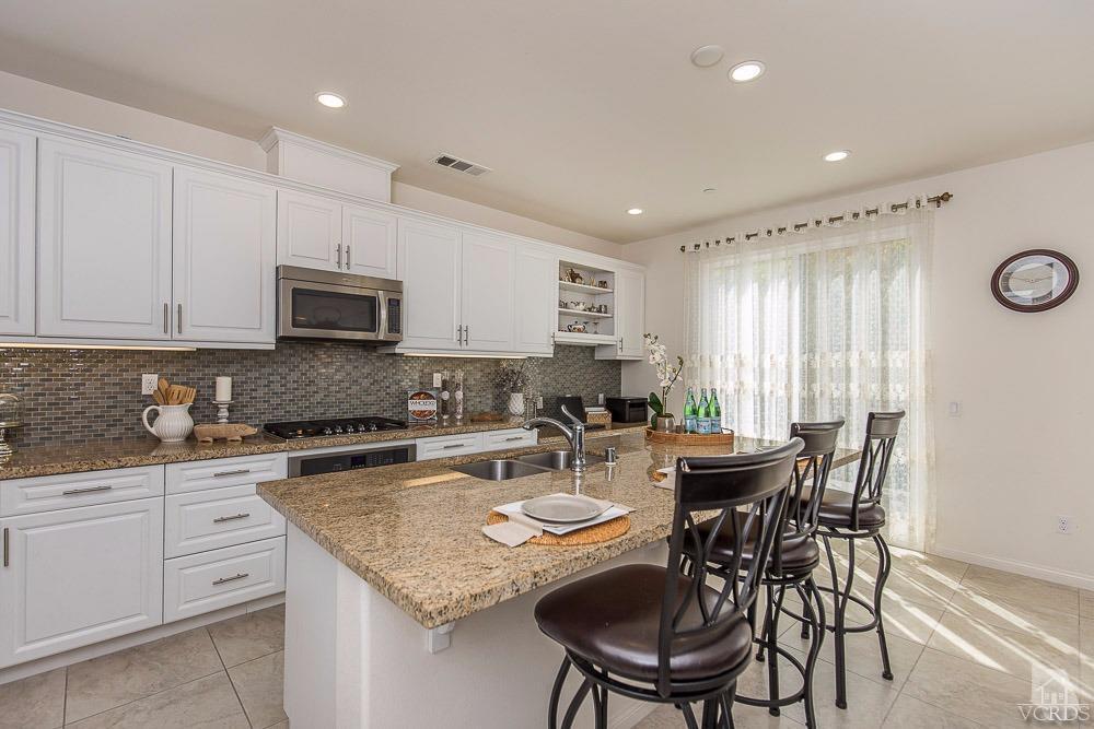 4885 Edenbridge Road Moorpark, CA 93021 - Photo 11 of 30 a kitchen with a stove a sink a dining table and chairs