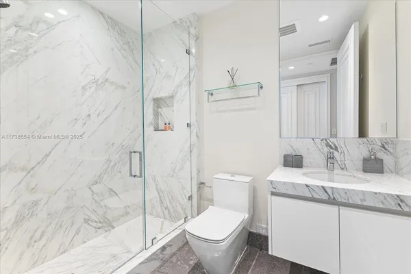 a bathroom with a granite countertop sink toilet and shower