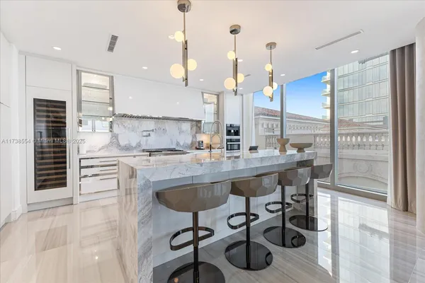a kitchen with kitchen island granite countertop a table chairs sink and cabinets