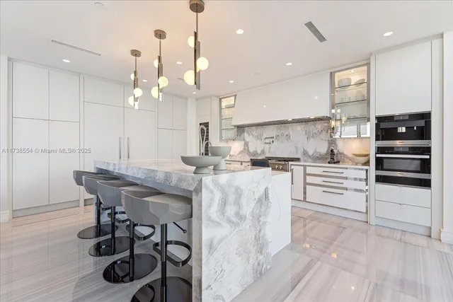a kitchen with kitchen island stainless steel appliances a dining table chairs sink and cabinets