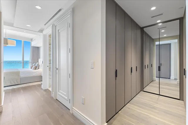 a view of a hallway with wooden floor and a bathroom