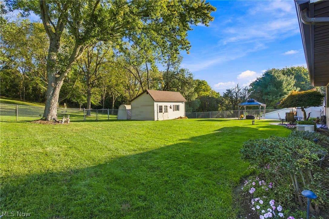 1211 Etter Road Mogadore, OH 44260 - Photo 20 of 48 Expansive fenced yard with mature trees, a detached storage shed, and a dedicated garden area