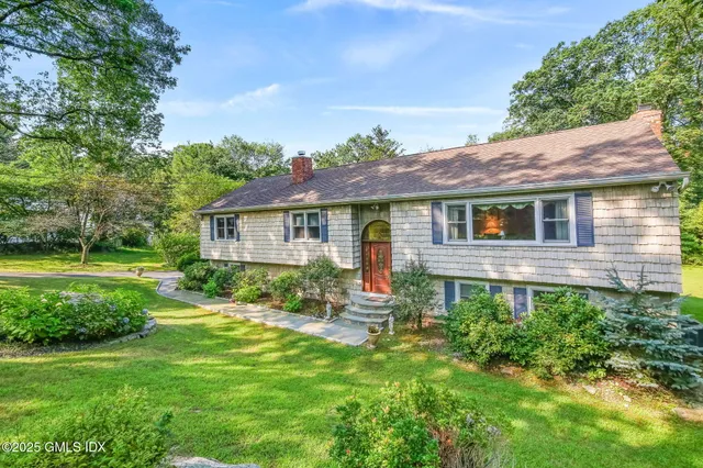 a backyard of a house with garden plants and outdoor seating
