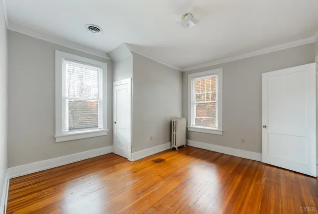 an empty room with wooden floor and windows