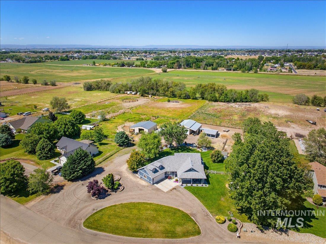 24623 Falcon Lane Caldwell, ID 83607 - Photo 40 of 40 Expansive property featuring a paved driveway, manicured lawns, mature trees, and a distant agricultural landscape