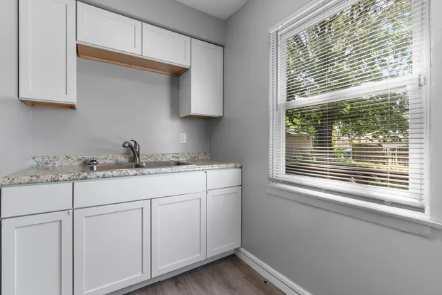 a kitchen with granite countertop white cabinets and a window