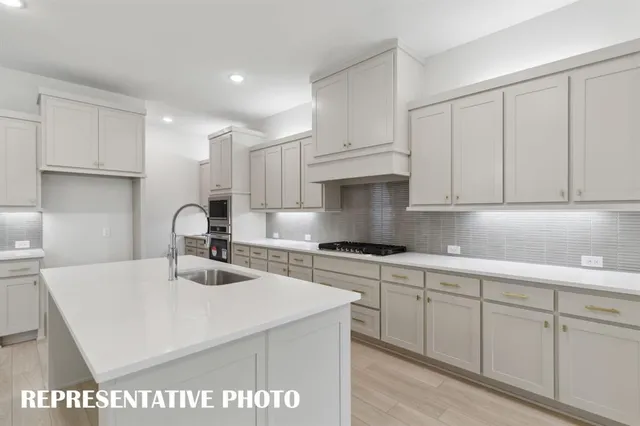 a kitchen with kitchen island a sink a stove and cabinets