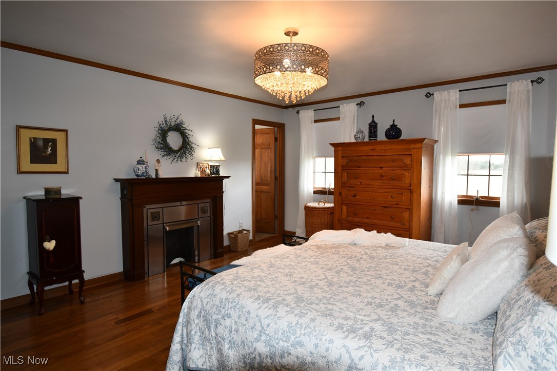 3180 West Calla Road Canfield, OH 44406 - Photo 38 of 49 Bedroom featuring an inviting chandelier, dark wood-style flooring, multiple windows, and ornamental molding