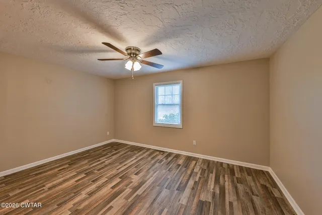 a view of a room with wooden floor and a ceiling fan